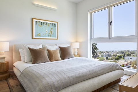 A bedroom with a large bed and a view of the city.