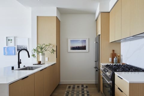 A kitchen with a sink, stove, and refrigerator.