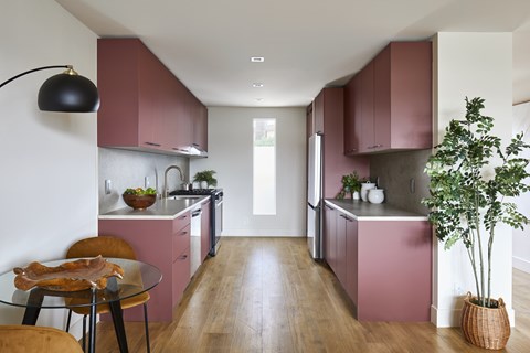 A kitchen with pink cabinets and a glass table.