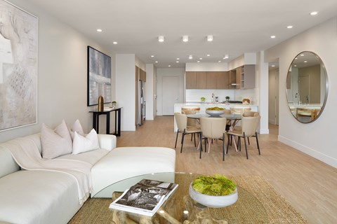 A modern living room with a glass coffee table and a white sofa.