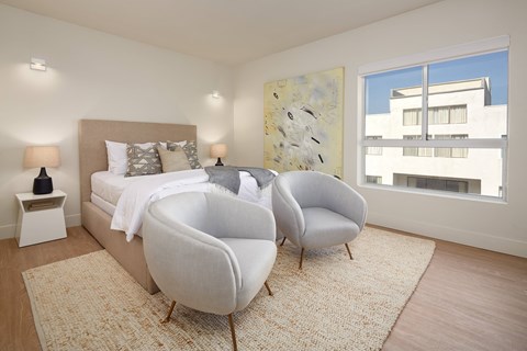 A bedroom with a large bed and two chairs.