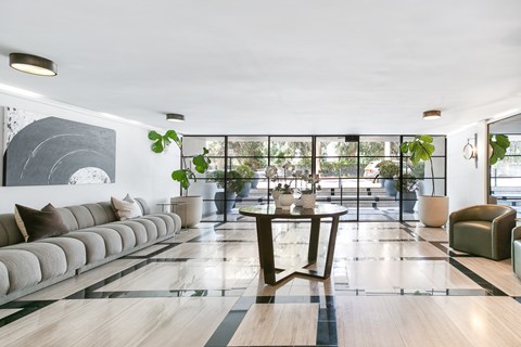 A modern living room with a long sofa, a coffee table, and a large abstract painting on the wall.