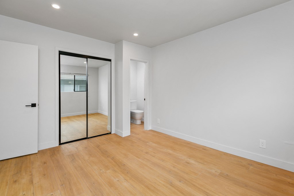 a living room with white walls and a sliding glass door to a bathroom
