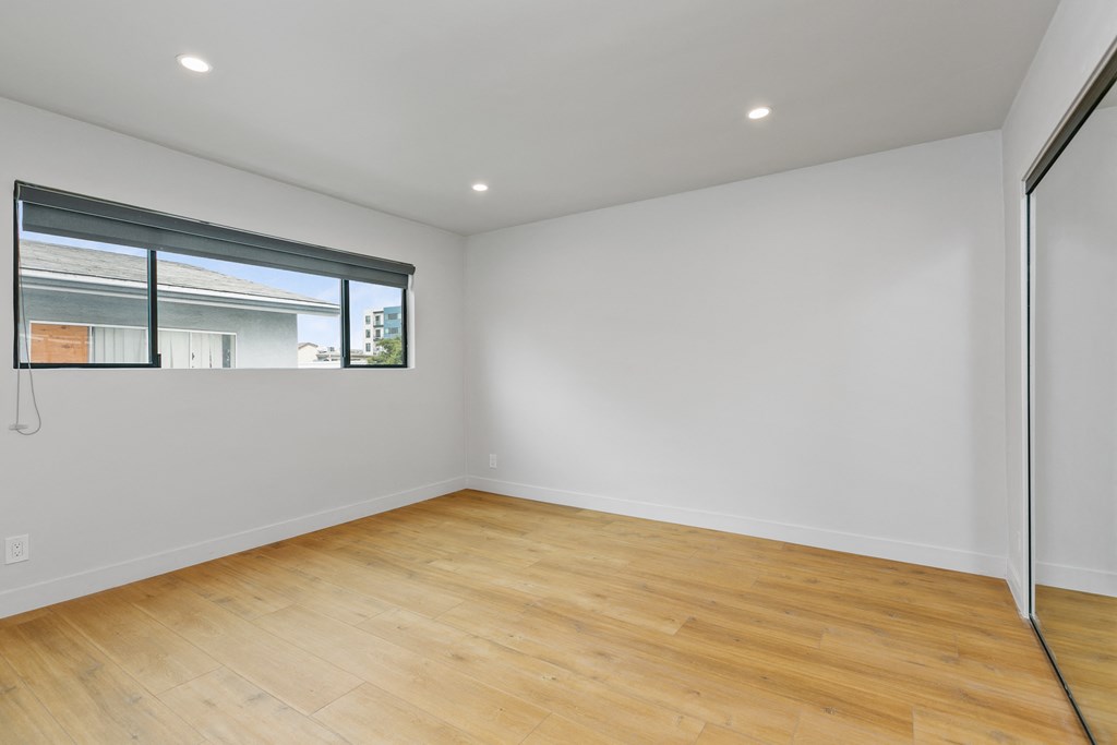 a living room with white walls and wood floors and a window