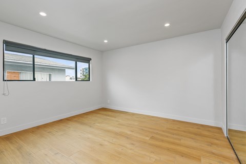 a living room with white walls and wood floors and a window