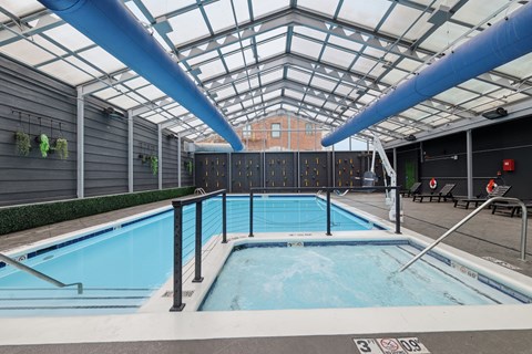 A large indoor pool with a glass ceiling and a blue pipe running along the top.