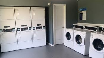 a row of washing machines and dryers in a laundry room