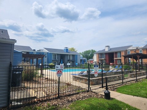 a pool with a fence in front of some apartment buildings