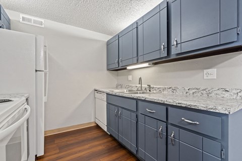 A kitchen with a white refrigerator and blue cabinets.