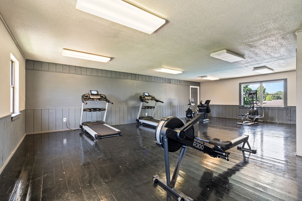 a gym with weights and exercise machines on a wood floor
