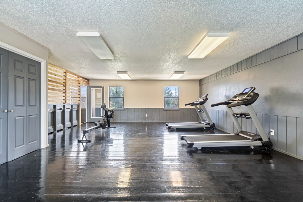 a gym with treadmills and weights in a large room with a door
