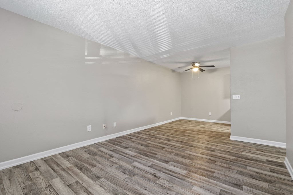 the spacious living room with wood flooring and a ceiling fan