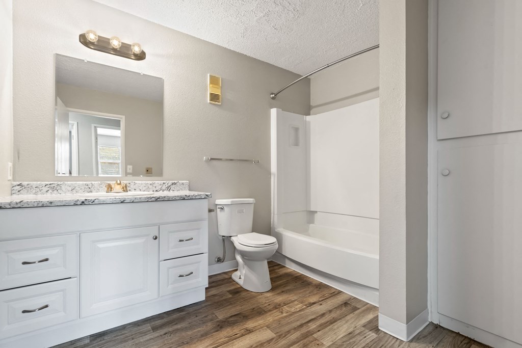 a bathroom with white cabinets and a toilet and a tub