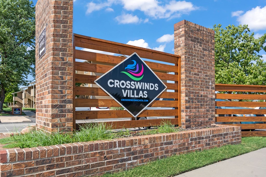 a sign for crosswinds villas in front of a wooden fence and brick