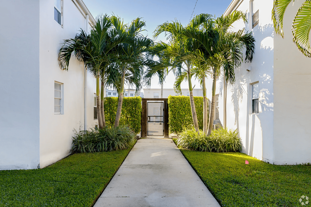 A white building with a pathway leading to a gate.