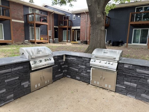 A BBQ grill is built into a stone wall.