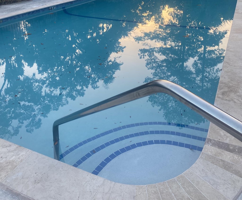 A pool with a metal handrail and blue tiles.