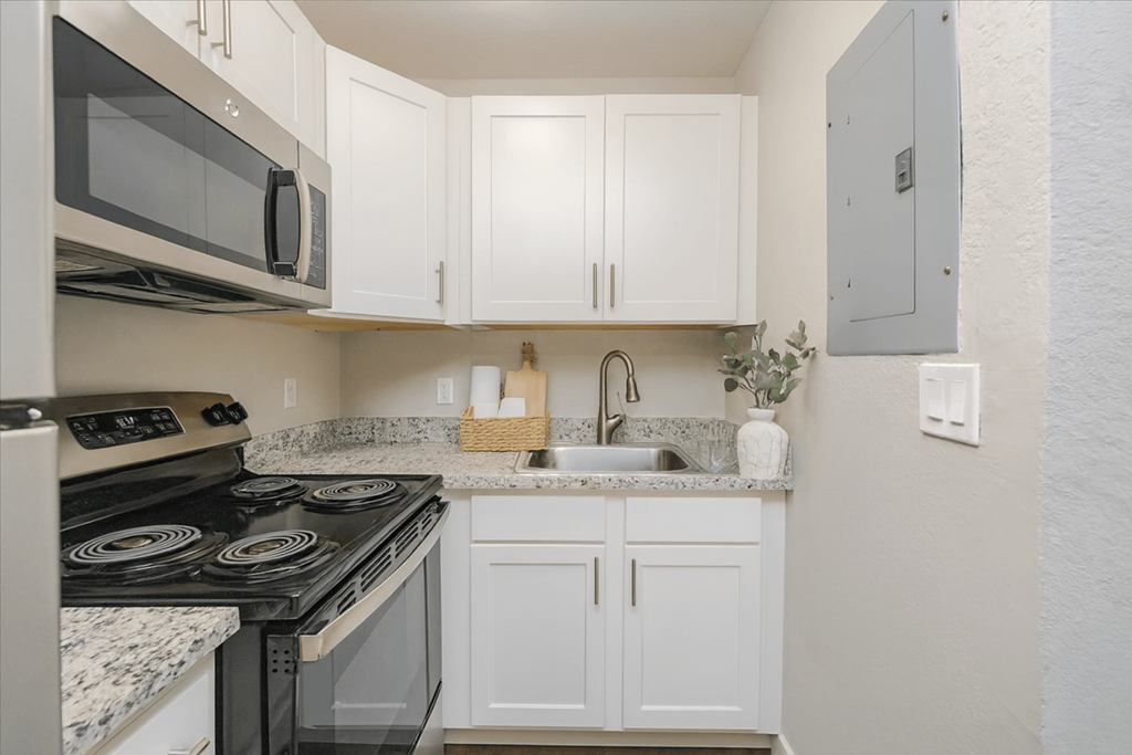 A kitchen with white cabinets and a black stove top oven.
