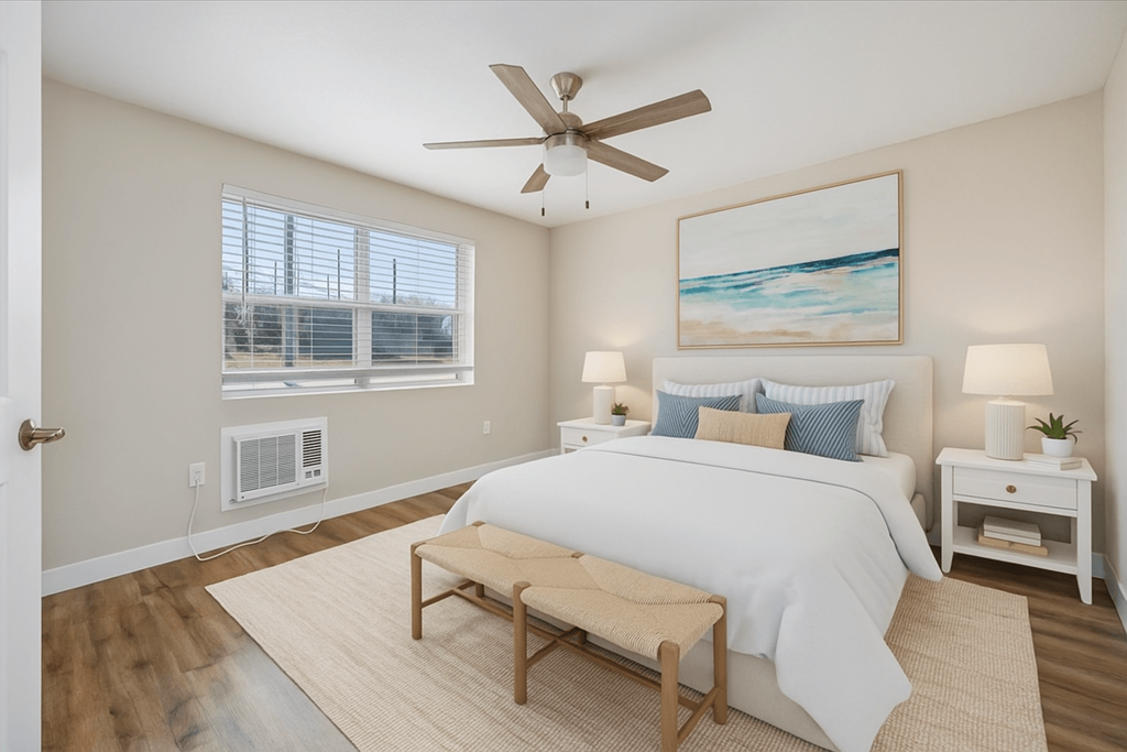 A bedroom with a large bed, a ceiling fan, and a painting on the wall.
