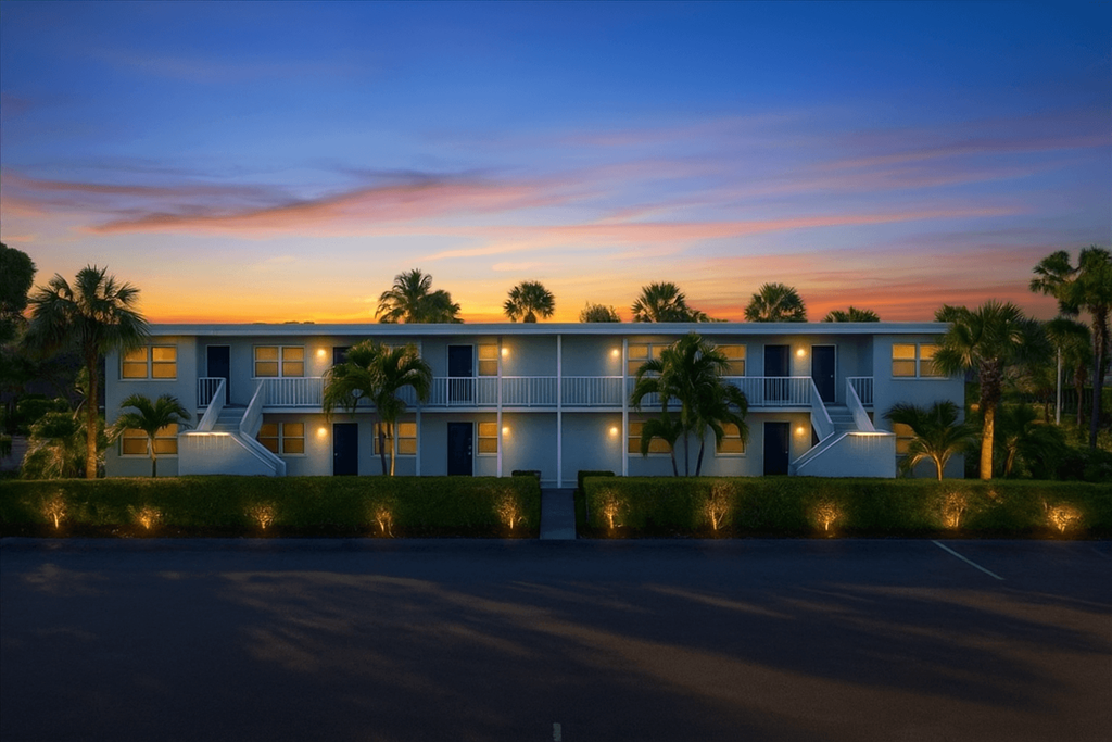 A modern building with a white exterior and palm trees in front.