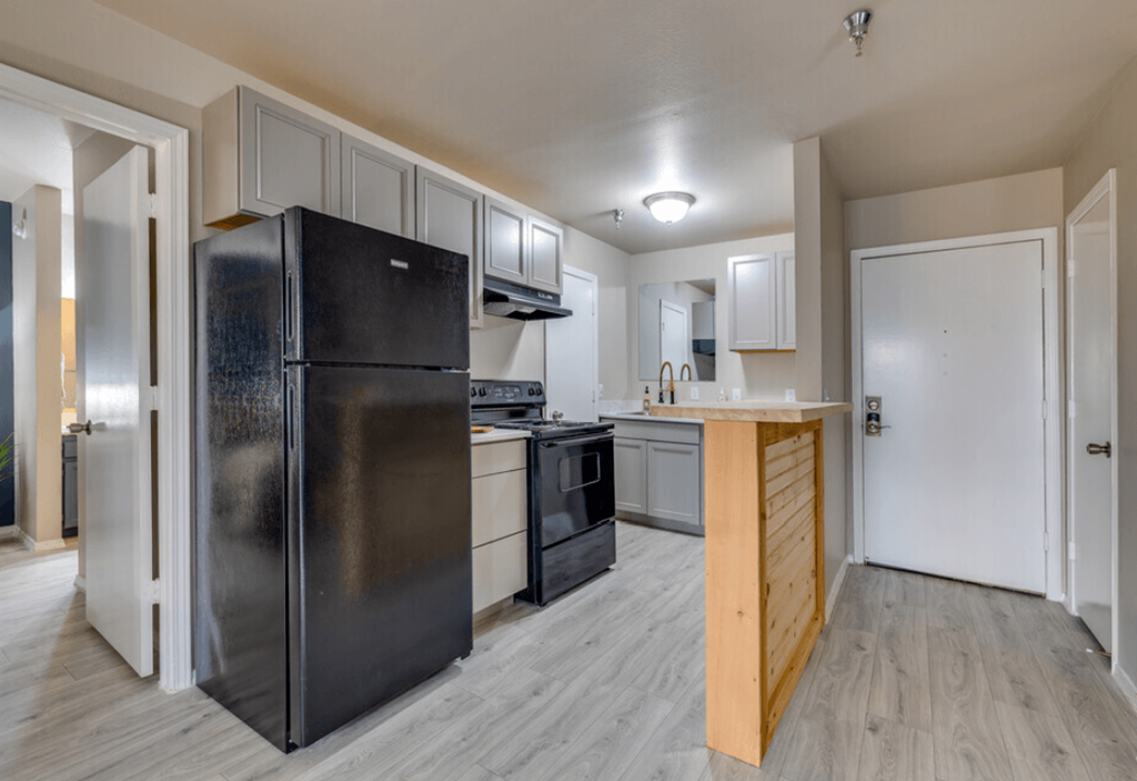 an empty kitchen with a black refrigerator and a black stove at The Lodge Apartments, Oklahoma