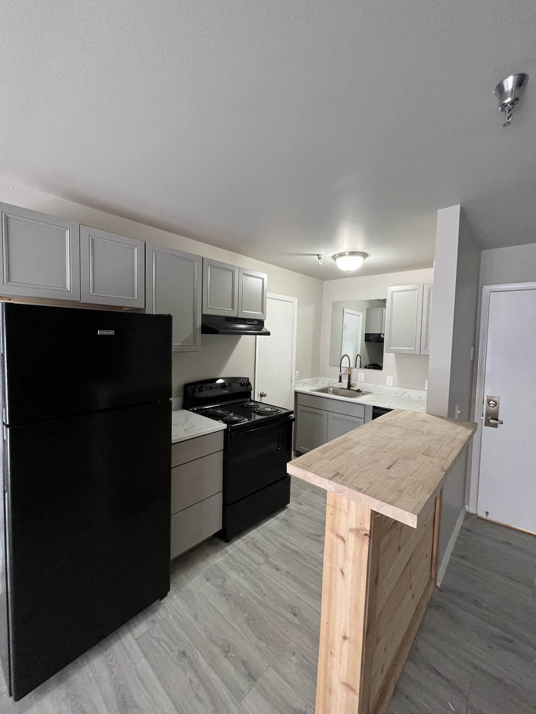 a kitchen with a black refrigerator freezer next to a stove top oven at The Lodge Apartments, Oklahoma, 74129