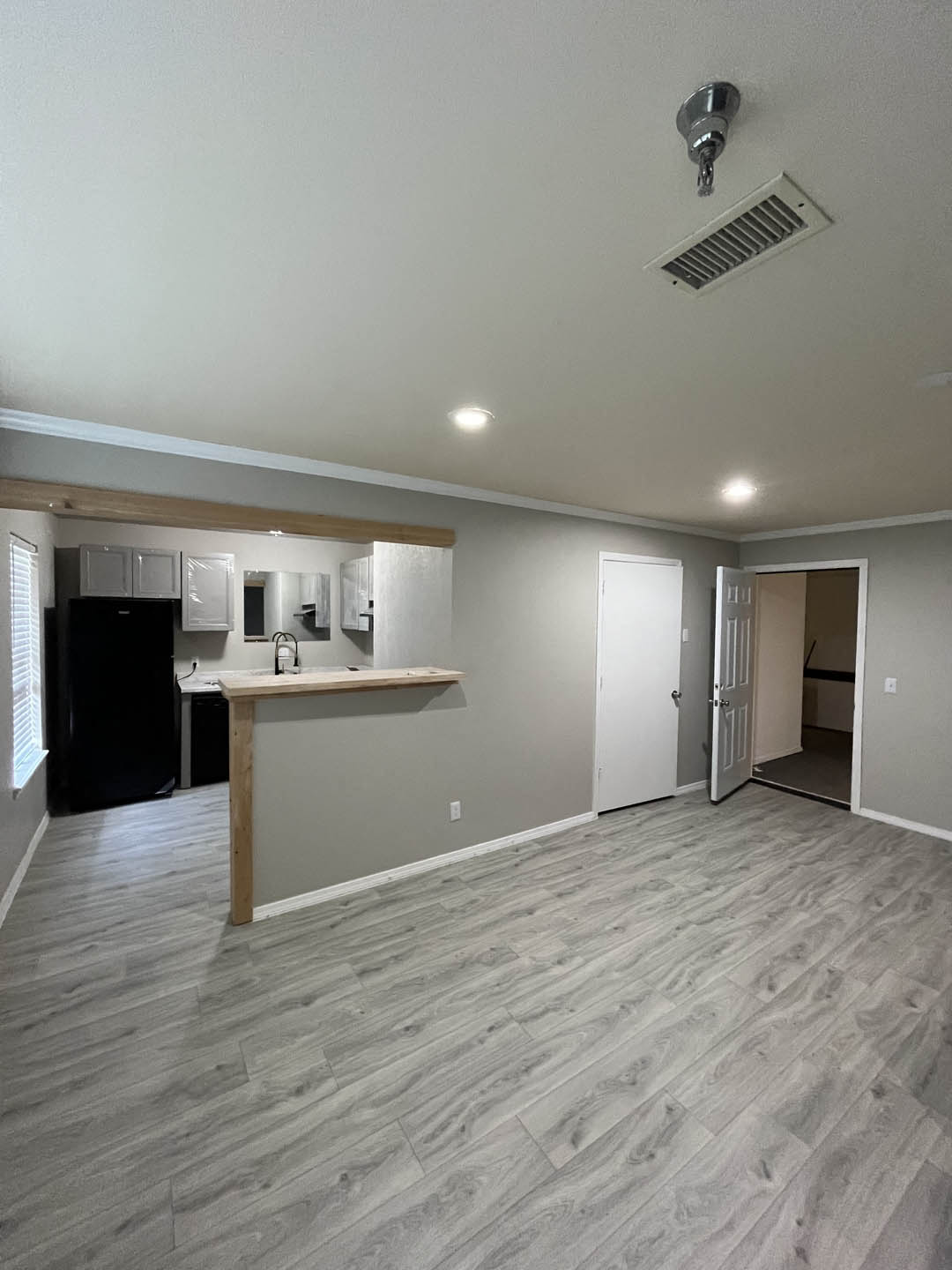 an empty living room with a kitchen in the background at The Lodge Apartments, Tulsa, 74129