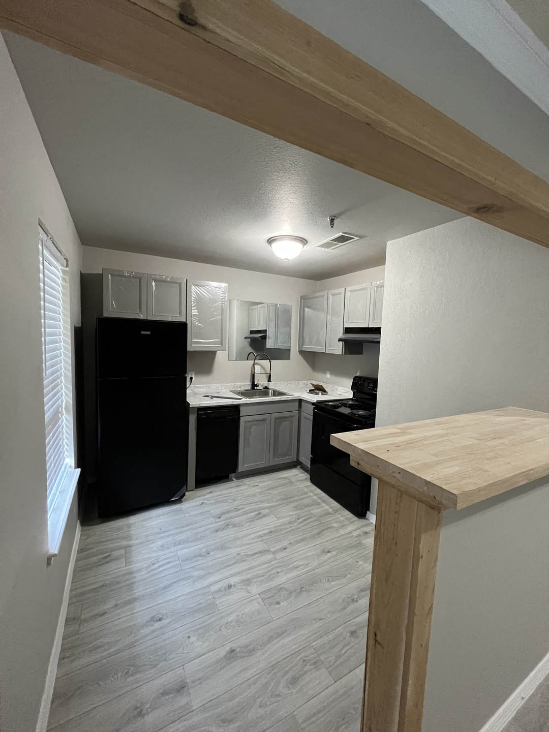 a small kitchen with white cabinets and black appliances at The Lodge Apartments, Tulsa, OK