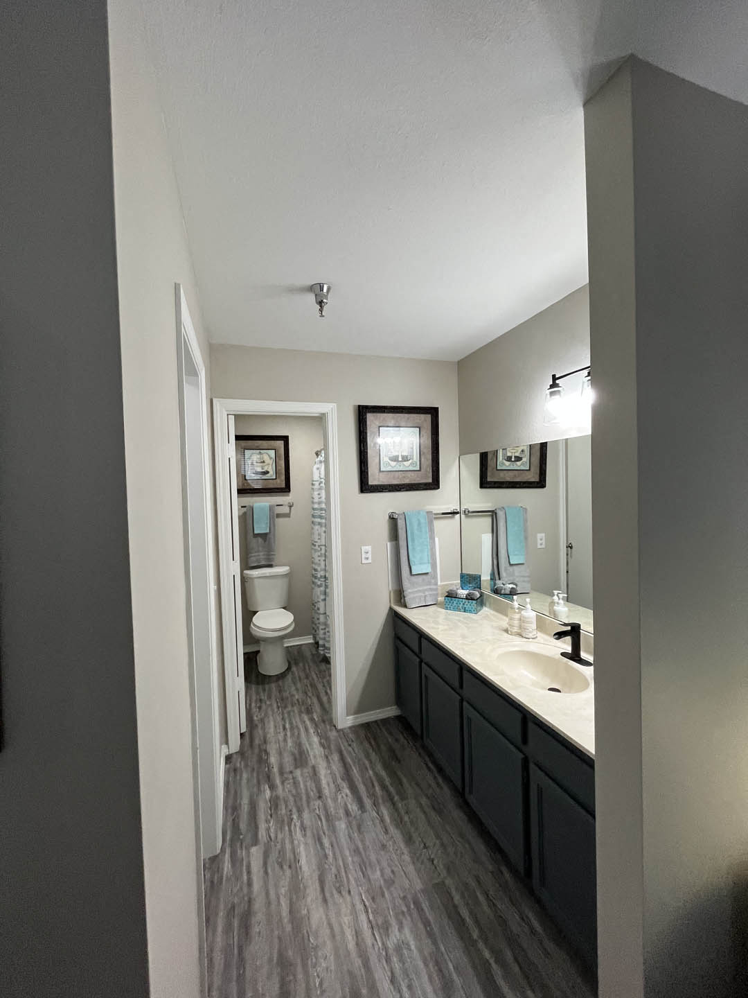 a bathroom with a toilet a sink and a mirror at The Lodge Apartments, Oklahoma, 74129