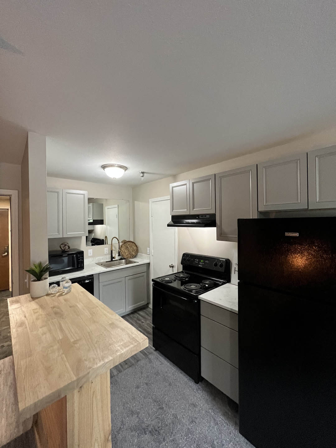a kitchen with white cabinets and black appliances at The Lodge Apartments, Tulsa Oklahoma