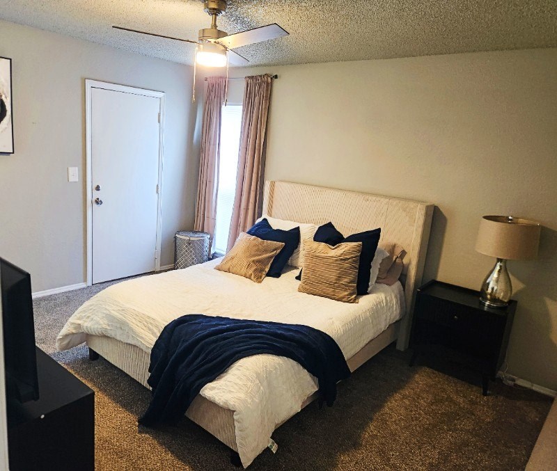 A bedroom with a bed, nightstand, and a ceiling fan.