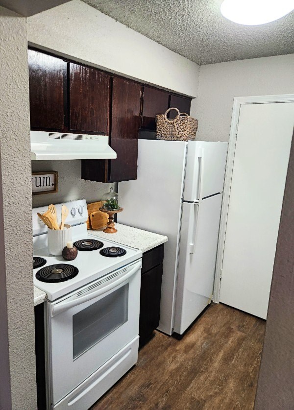 A kitchen with a white stove top oven and a white refrigerator.