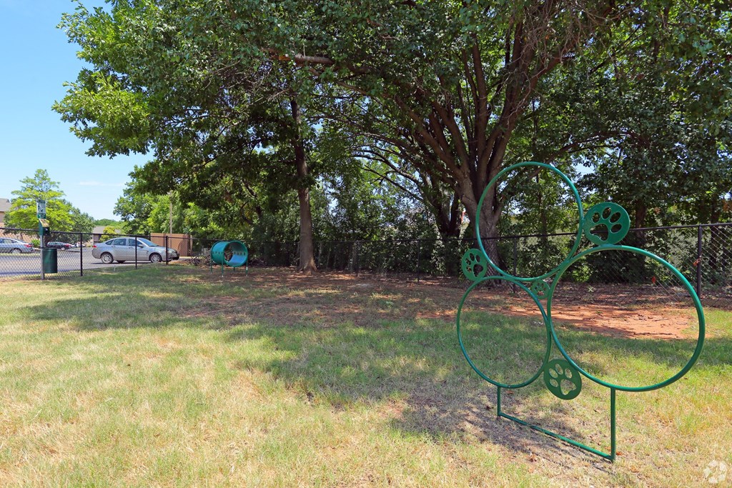 A green metal sculpture of a dog is in a grassy area.