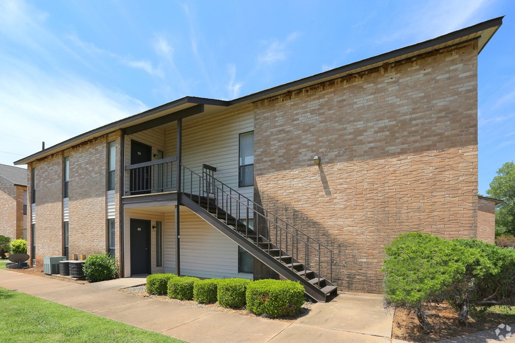A brick building with a balcony and stairs leading to the entrance.