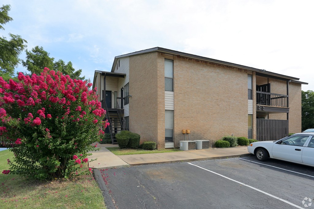 A white car is parked in front of a brick building.