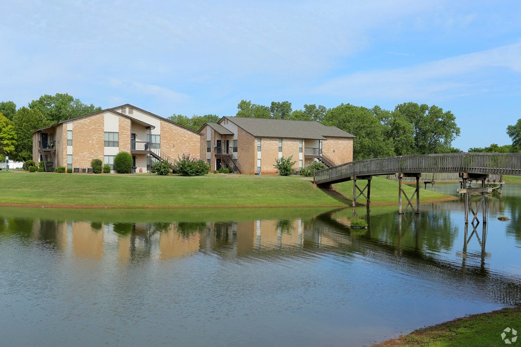 A serene lake with a bridge and houses in the background.