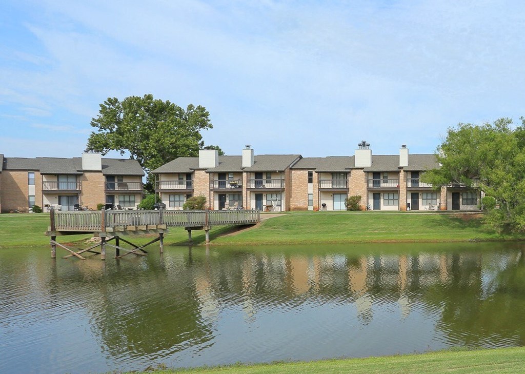 A row of houses with a bridge over a pond in front.