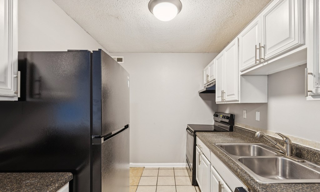 A kitchen with a black refrigerator and white cabinets.