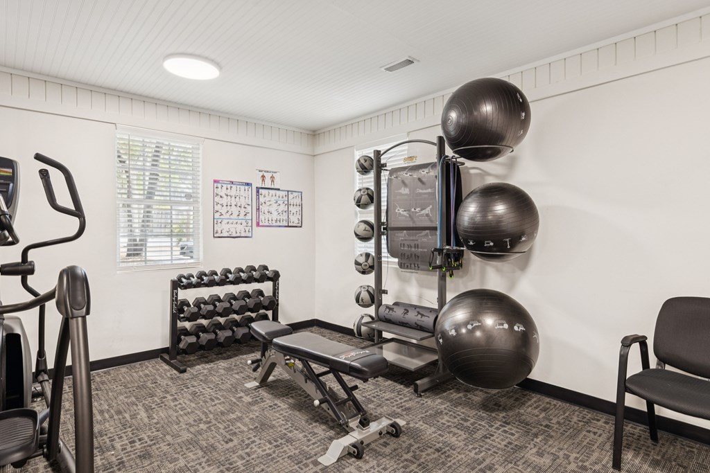 A gym room with a variety of equipment including a treadmill, weights, and a bench.