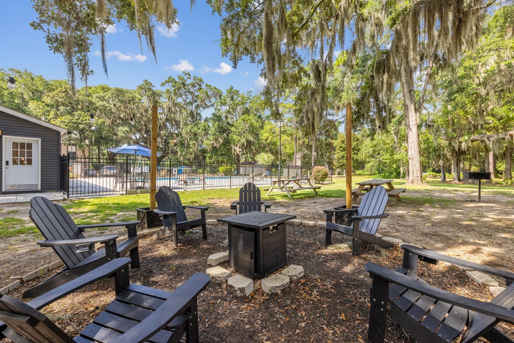 A backyard with a fire pit and chairs.