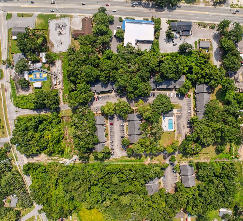 A bird's eye view of a residential area with houses, trees, and a swimming pool.