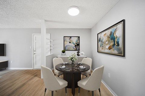 A dining room with a table set for two and a painting on the wall.