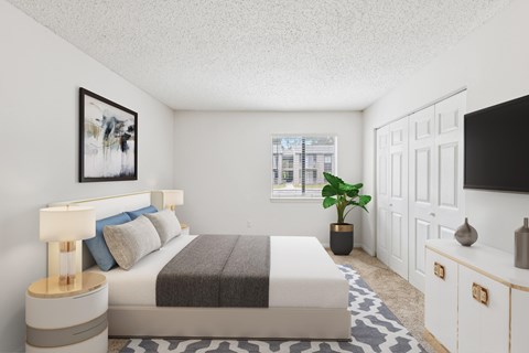 A bedroom with a bed, nightstand, and a plant.