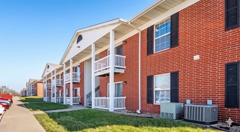 A row of red brick apartment buildings with white balconies.