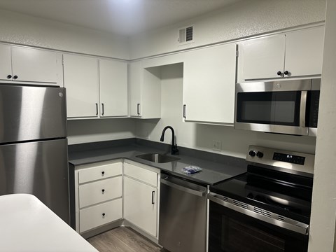 A kitchen with white cabinets and stainless steel appliances.
