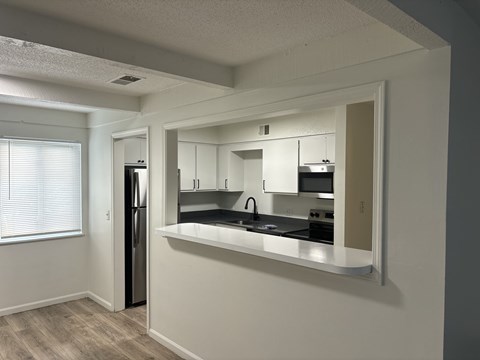 A kitchen with white cabinets and a black fridge.