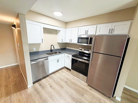 A kitchen with a refrigerator, oven, and microwave.