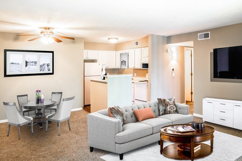 A living room with a grey couch, a coffee table, and a dining table with chairs.