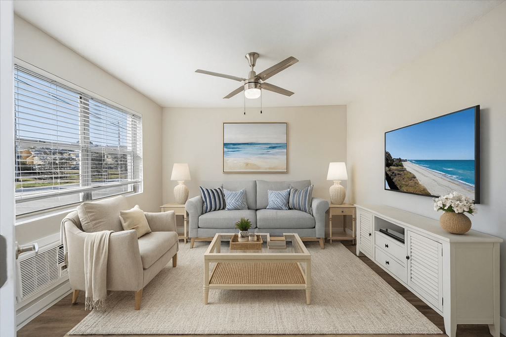 A living room with a grey couch, a coffee table, and a painting of a beach scene on the wall.