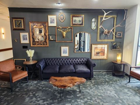 a living room with a black couch and a wall filled with paintings and mirrors